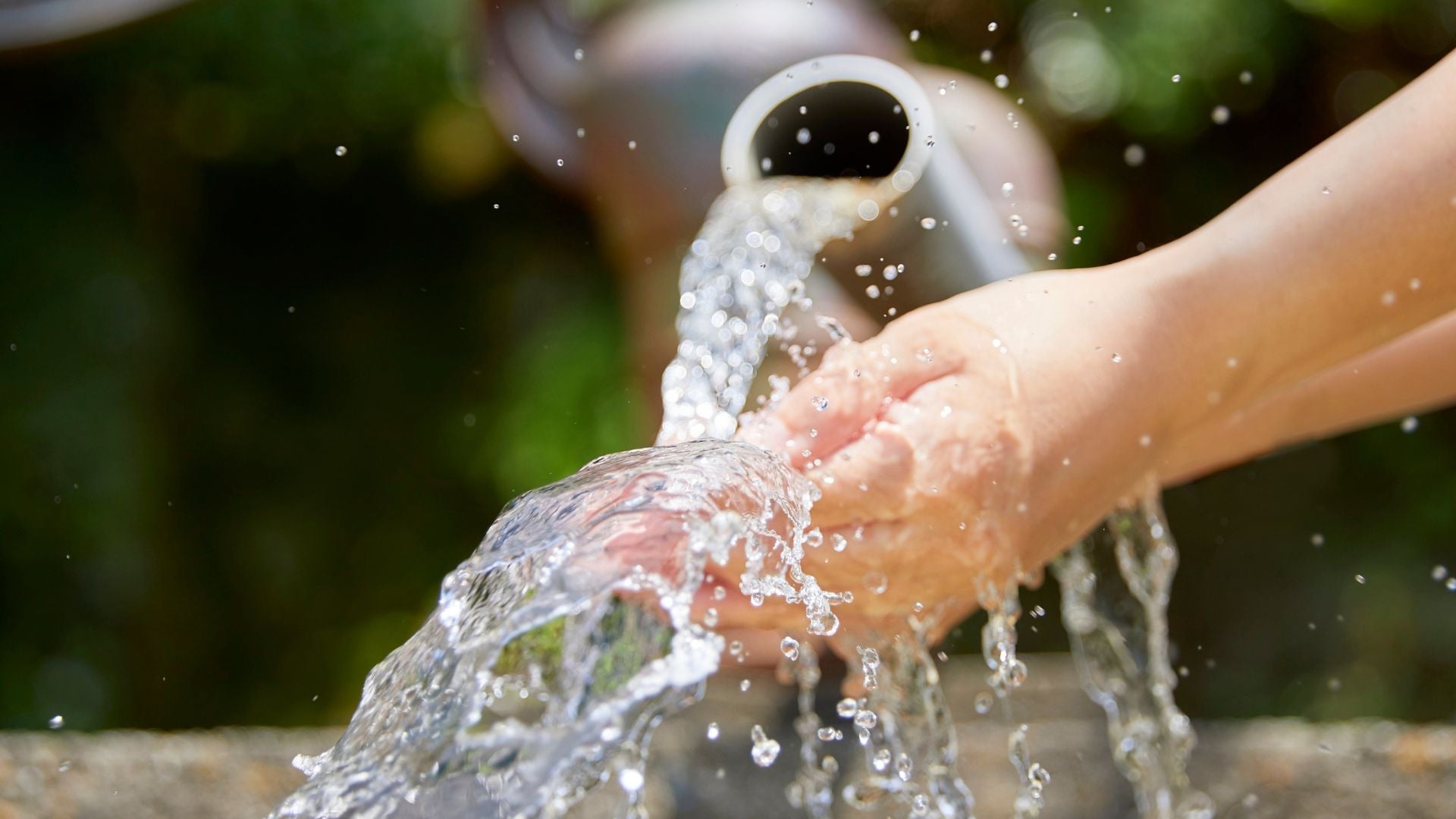 Hands in water running from a pipe