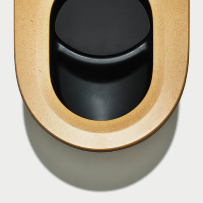 Close-up of a black toilet seat with beige rim on a white background